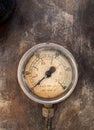 Old round pressure meter with numbers on the gauge on a rusty metal background