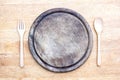 Old round wooden cutting board with spoon and fork on a table background.