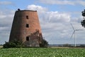 Old ruined abandoned windmill tower with electric turbines generating power in the background Royalty Free Stock Photo