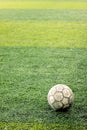 Old and ruined ball on new indoor soccer field made of artificial grass. Royalty Free Stock Photo