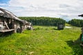 Old ruined buildings in the village, rickety street wooden toilet on the background of beautiful nature, lake, forest, hills.