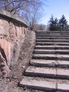 An old ruined concrete staircase with broken steps on the street near the fence