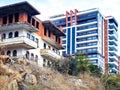 Old ruined house on the background of a new modern house. Facades of old and new houses in one frame. Time contrast Royalty Free Stock Photo