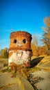 an old ruined red brick water tower, painted by a street artist to look like a Jolly giant.