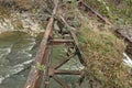 An old, ruined, rusty, metal bridge over a turbulent mountain river. Royalty Free Stock Photo