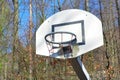 Old run down and rusty basketball basket on play ground surrounded by forest