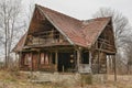 Old rural abandoned wooden collapsing house against cloudy sky in autumn season.