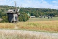 An old rural landscape with windmills against the backdrop of a lawn and dense forest