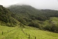 An old rural path iun middle of a green countryside with cloudy forest mountain Royalty Free Stock Photo