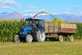 An old rural tractor collects a rich crop of corn from the field. Combine harvester is working in the field