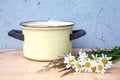 Old rusitic yellow cooking pot with daisies on wooden table