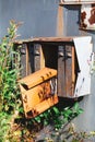 An old russian teal metal postbox with one orange rusty box out of the container. Tall grass swaying in front of the postbox and