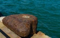 Old rust-covered mooring bollard on a pier against the backdrop of turquoise water. Close-up. The embankment Royalty Free Stock Photo