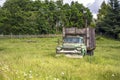 Old rust green truck with wooden trailer standing on the meadow with high grass as a symbol of a past life Royalty Free Stock Photo