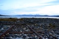 Old rusted boat landing ramp on sea shore with fjord and snowy mountain Royalty Free Stock Photo