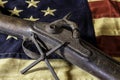 Old musket rifle and metal cross on American flag