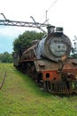 OLD RUSTED STEAM LOCOMOTIVE AT AN ABANDONED STATION WITH OVERHEAD GANTRY Royalty Free Stock Photo
