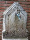 Old rusted street water pump on brick wall background