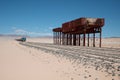 an old, rusted structure stands in the desert with tracks running down the length Royalty Free Stock Photo