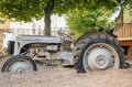 Old rusted tractor with wheels in sand as a part of playground for kids