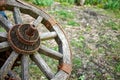 An old, rusted wagon wheel, a relic of a bygone era, lying forgotten in a grassy field. A wooden, old cartwheel with a metal rim.