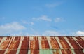 Old rusted and weathered steel quonset hut roof against a blue sky with fluff clouds Royalty Free Stock Photo