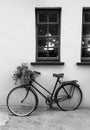 Old rustic bike with flowers in basket leaning against wall