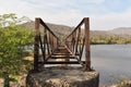 An old rustic and dark steel river bridge across a river Royalty Free Stock Photo