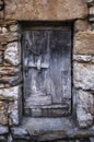 An old, rustic and deteriorated wooden door framed in a blue-gray tone on a stone wall in warm tones Royalty Free Stock Photo