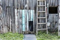 Old rustic gray blue wooden plank wall with dog walkway door and wooden staircase, white horseshoe above the entrance Royalty Free Stock Photo