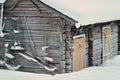 Old rustic house made of timber and covered in snow. The building has yellow or orange wooden doors. Some tools on the side of the Royalty Free Stock Photo