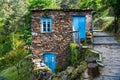 Old rustic stone house with bright blue doors and windows in a lush forest landscape in a village in Portugal Royalty Free Stock Photo