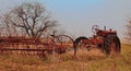 An old rustic tractor in a field attached to a plow