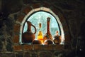 Old rustic wine bottles, jugs on a small cellar window on a stone wall Royalty Free Stock Photo