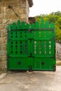 Old rustic wood gate painted in green with masive metal hinges