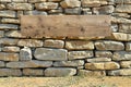 Old rustic wooden empty frame on grunge handmade stones wall on a sunny day Royalty Free Stock Photo