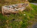 Old wooden boat ashore in a field.