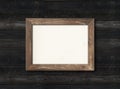 Old rustic wooden picture frame hanging on a black wall. Horizontal picture Royalty Free Stock Photo