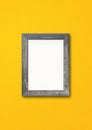 Old rustic wooden picture frame hanging on a yellow wall Royalty Free Stock Photo