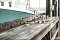 An old rustic and worn wood fish cleaning station on the dock of a pier with a boat nearby Royalty Free Stock Photo