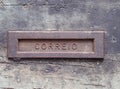 an old rusting iron letterbox in a black wooden door with chipped peeling paint with the word correio Royalty Free Stock Photo