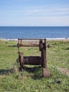 An Old rusting Manual Boat Winch used for hauling in Fishing Boats lies abandoned on the Grassy Bank behind the Beach.