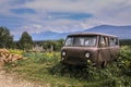 Old rusty abandoned minibus in the mountain village, pile of firewood, East Kazakhstan