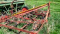 Old, rusty and abandoned red agricultural cultivator next to an old tractor Royalty Free Stock Photo