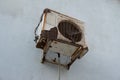 Old rusty air conditioner outdoor unit. Hanging on a white wall background Royalty Free Stock Photo