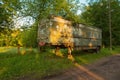 Old rusty aluminum steel metal caravan trailer painted in military khaki green in bright happy summer sunset light. Atmospheric