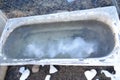 An old rusty bathtub on the street, ice