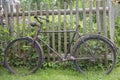 Old rusty bicycle leaning against a wooden fence Royalty Free Stock Photo