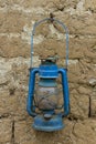 Old rusty blue petroleum lantern on a mud brick wall Royalty Free Stock Photo