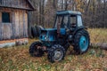 Old rusty blue tractor in a wood. Russian village.